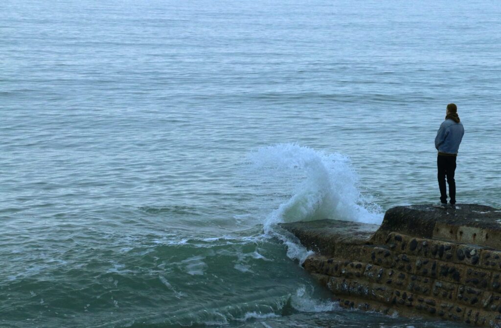 man by ocean in blog about why grief comes in waves by erin moore centered one