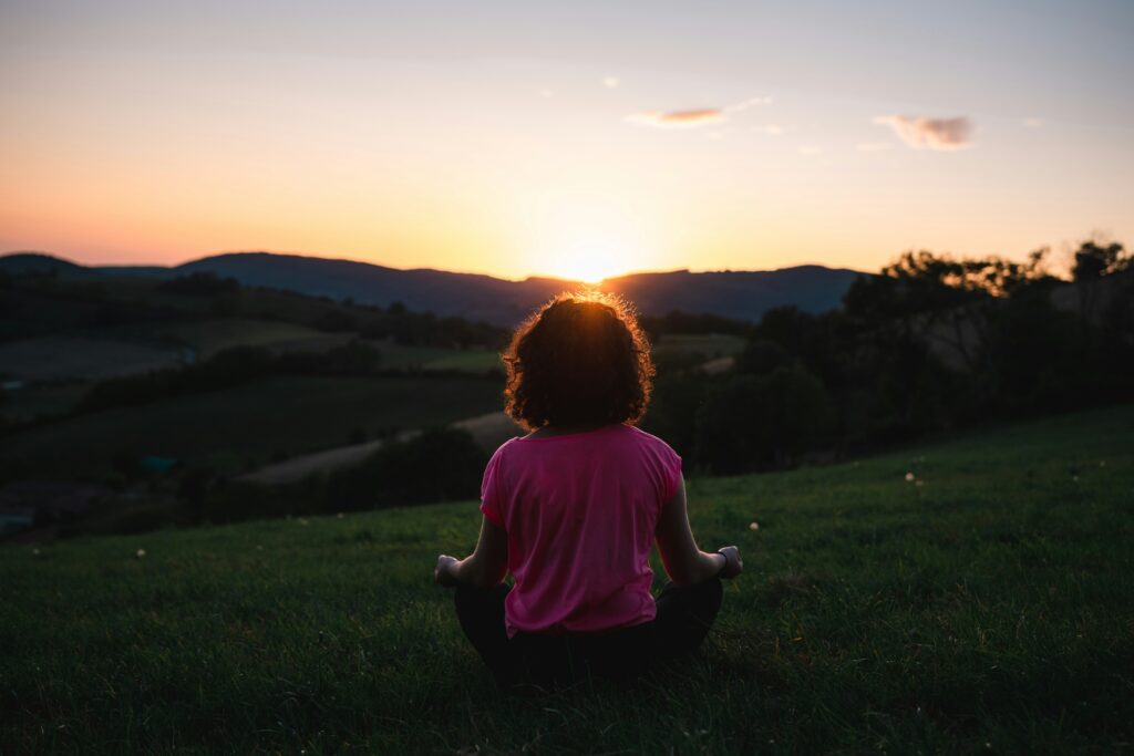 girl meditating at sunset in blog about what is people pleasing by erin moore centered one